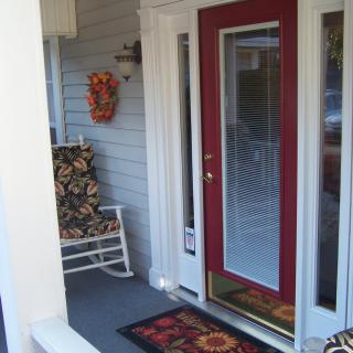 A welcoming front porch with a red door, a rocking chair, and decorative elements.
