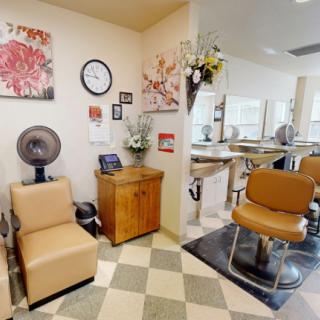 A cozy hair salon interior featuring styling chairs, a mirror, and a hair dryer station.