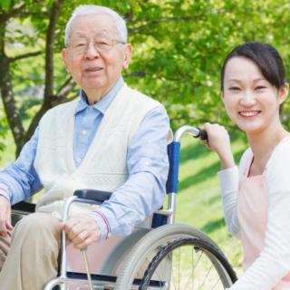 An elderly man in a wheelchair enjoying the outdoors with his caregiver.