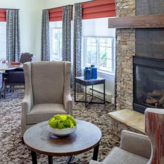 A cozy living room area with armchairs, a fireplace, and a coffee table decorated with green apples.