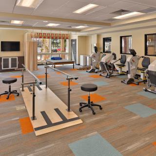 A well-equipped rehabilitation therapy room featuring exercise stations and a balance beam.