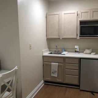 A small, compact kitchen area in an apartment with wooden cabinets and basic appliances.