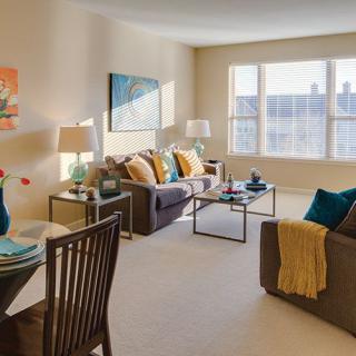 A cozy and well-lit living room with modern furnishings, including sofas, tables, lamps, and decorative elements.