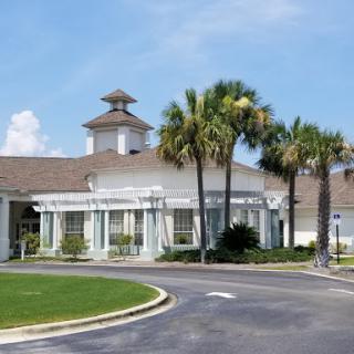 A picturesque residential community building surrounded by palm trees on a sunny day.