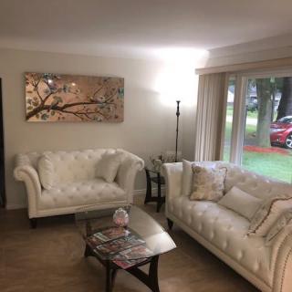 A cozy and modern living room with elegant cream sofas, a glass coffee table, and a floor lamp complementing the chic wall art.