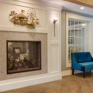 A cozy living room with a modern fireplace and a blue chair.