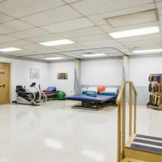 A physical therapy room equipped with exercise machinery and a therapy bed.