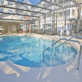 An enclosed indoor swimming pool area in a residential setting with sunlight streaming through the glass roof.