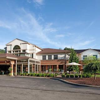 Exterior view of a hotel with clear skies and surrounding greenery.