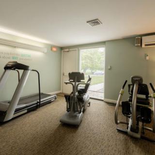 A small gym with exercise equipment including a treadmill and stationary bikes.