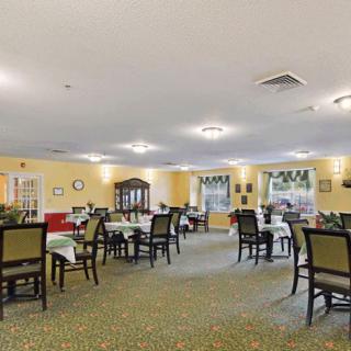 A spacious dining room with neatly arranged tables and chairs, featuring large windows and soft lighting.