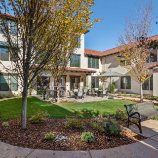 A peaceful courtyard with seating and landscaping in front of a two-story building.