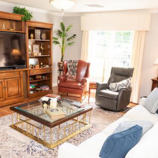 A cozy living room with a sofa, two chairs, a coffee table, and a large television in a wooden entertainment center.
