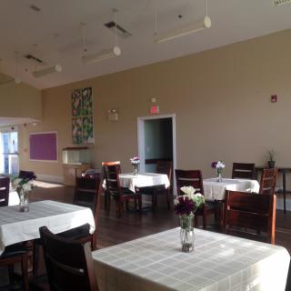 A quiet dining area with tables and chairs arranged neatly, each table adorned with a small vase of flowers.
