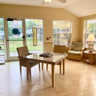A cozy living room with a table, chairs, and large windows allowing natural light.