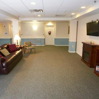 A cozy living room with a sofa, television, and carpeted floor.