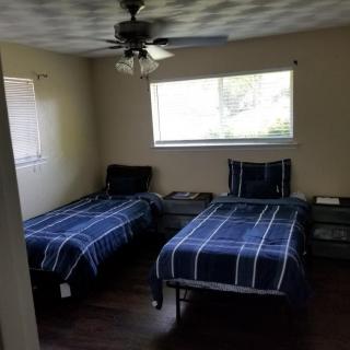 A bedroom with two twin beds, featuring blue plaid bedding and a window letting in natural light.