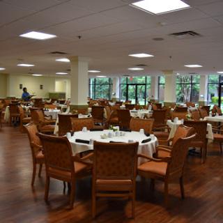 A spacious dining area with neatly arranged tables and chairs, featuring large windows that provide natural light.