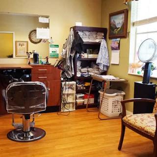 A cozy hair salon with a barber chair, mirror, and various hair products on display.