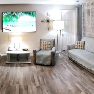 A modern living room with a cozy armchair, sofa, and a wall-mounted television.