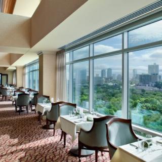 A spacious restaurant with large windows offering a panoramic city view.