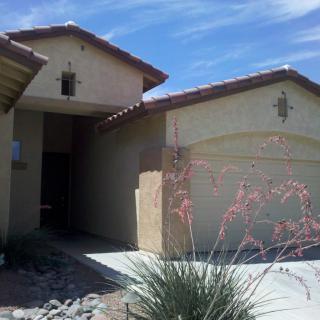 A desert-style suburban house with a stucco exterior and a well-maintained front yard.