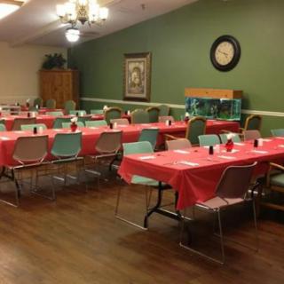 A community dining room prepared for an event with tables covered in red tablecloths.