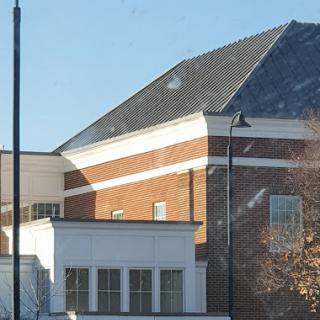A close-up view of a brick building with a sloped roof under clear skies.