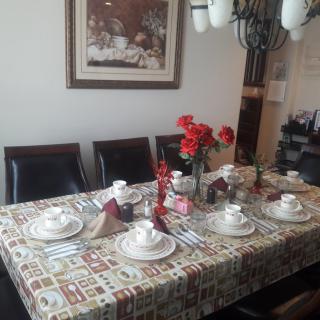 A neatly set dining table with dinnerware and a floral centerpiece.