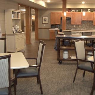 A modern dining area featuring wooden furniture and a spacious kitchen in the background.