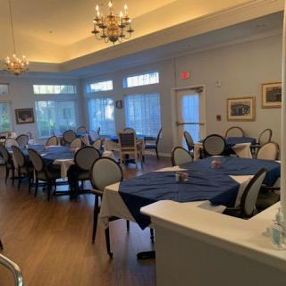 An elegant dining area with neatly arranged tables and chairs, featuring chandeliers and soft lighting.