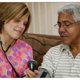 A nurse checks the blood pressure of an elderly patient at home.