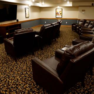 A cozy home theater room with leather seating and a large television.