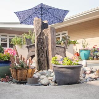 A tranquil garden scene with potted plants and a decorative umbrella.