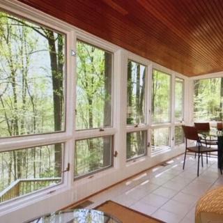 A modern sunroom with large windows offering a scenic view of nature.