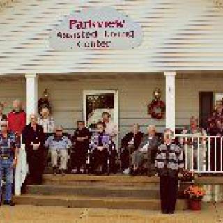 A group of elderly individuals gathered at the entrance of Parkview Assisted Living Center.