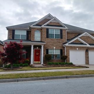 A suburban two-story brick house with a red front door and attached garage.