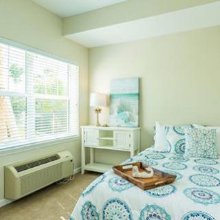 A bright and cozy bedroom with a neatly made bed and patterned bedding.