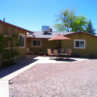 A sunny backyard with a patio featuring outdoor furniture and an umbrella.