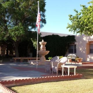 A serene courtyard with a fountain and seating area under the shade of trees, featuring an American flag.