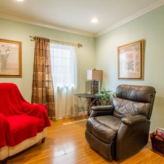Cozy living room with a comfortable armchair and sofa, adorned with artwork and natural light.