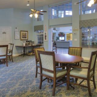 A cozy dining area with tables and chairs, illuminated by ceiling lights and a fan.