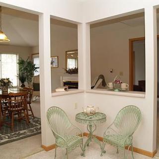Cozy dining area with green chairs and a small table, featuring an open view into the living room.