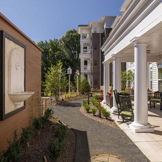 A well-landscaped outdoor area featuring a pathway, columns, and a patio adjacent to buildings.