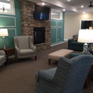 A cozy living room with modern decor, featuring a fireplace, armchairs, a sofa, and a television.