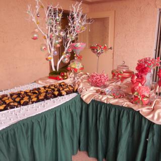 A festive buffet table decorated with a green tablecloth, featuring a variety of foods and holiday-themed decorations.