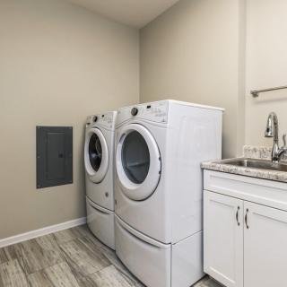 A modern laundry room featuring a washing machine, dryer, and sink.