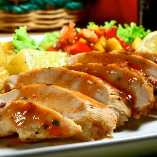 A delicious plate featuring sliced grilled chicken, accompanied by colorful vegetables and crispy potato chips.