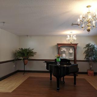 A spacious room featuring a grand piano, elegant chandelier, and tasteful decor.