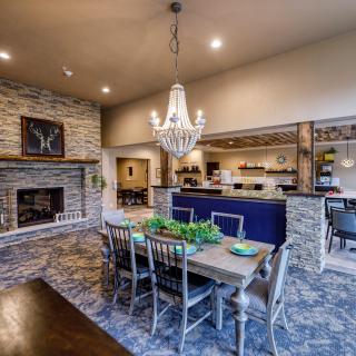 A stylish dining area with a rustic stone fireplace and an open kitchen featuring a chandelier and elegant decor.